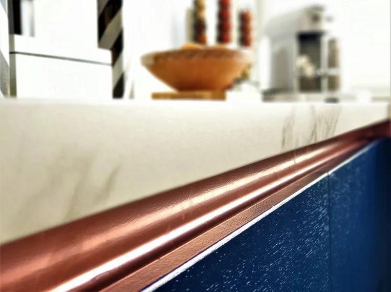 Close-up of copper countertop trim against navy cabinetry