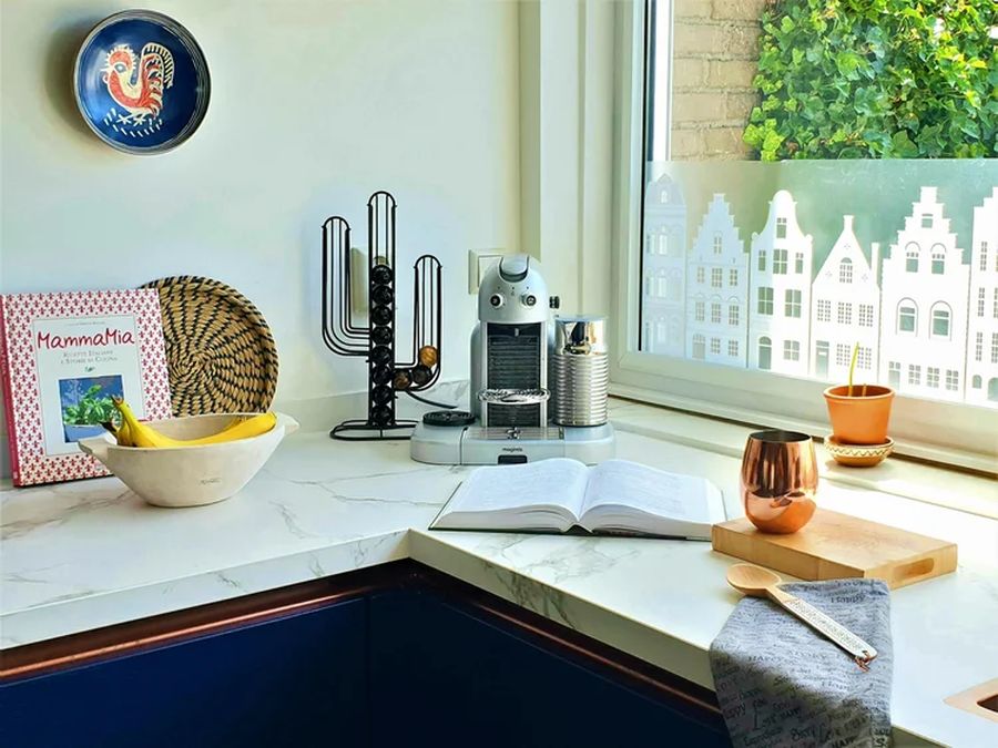 Navy blue kitchen cabinets with copper tap and marble countertop