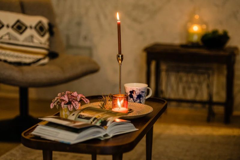 Cozy coffee table styling with lit candle, plants, and magazines