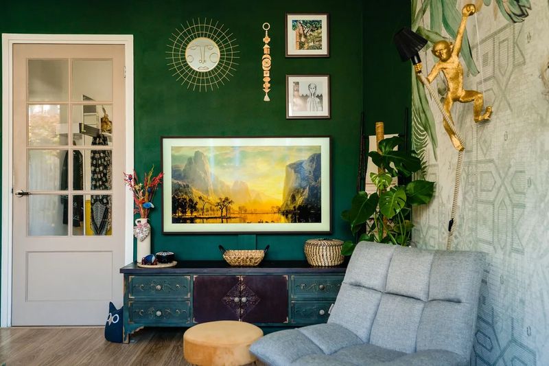 Deep green wall with botanical mural and gold wall lamp